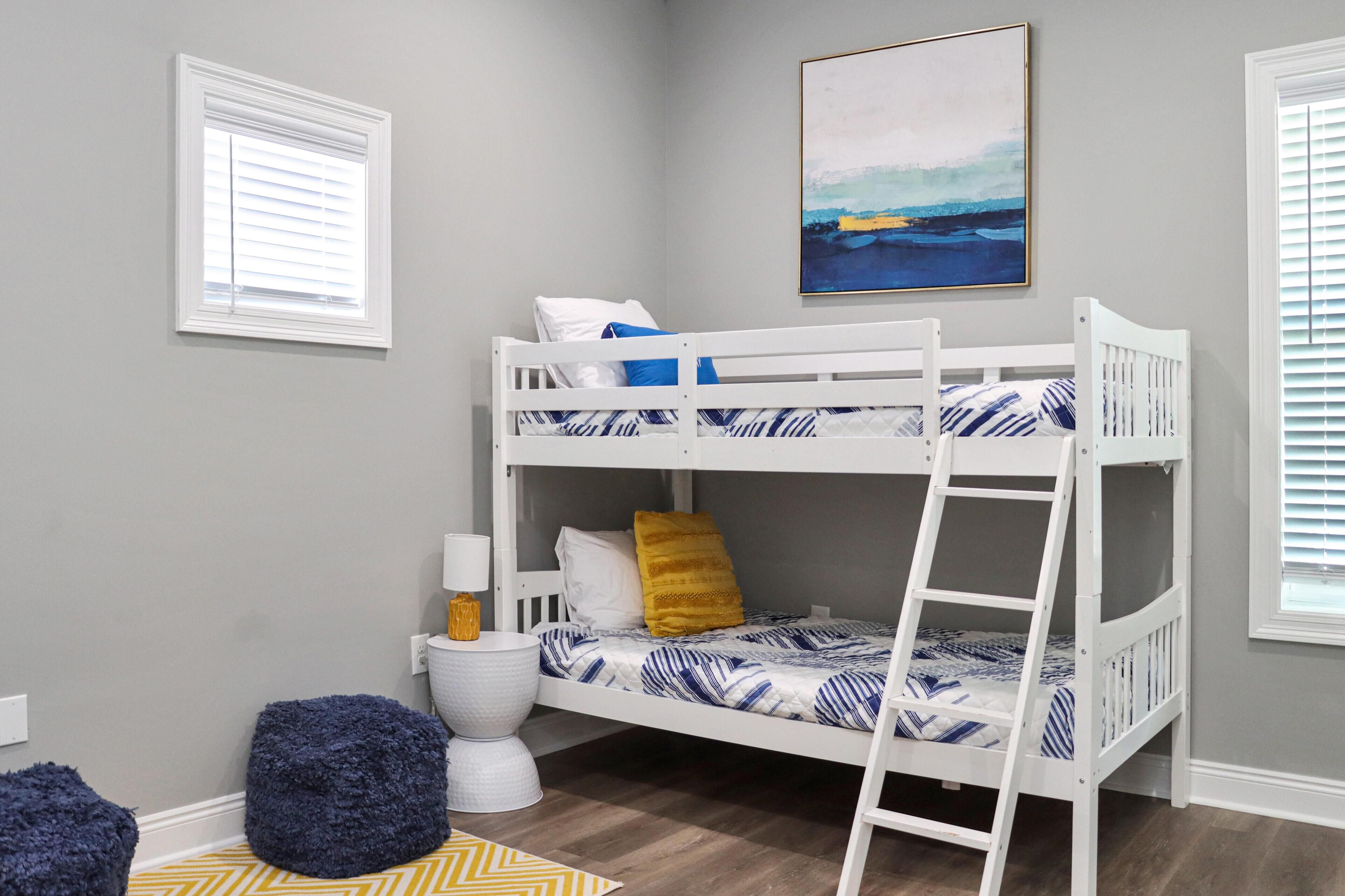 A bunk bed with two levels, a bedside table with a lamp, a chair, and a rug.