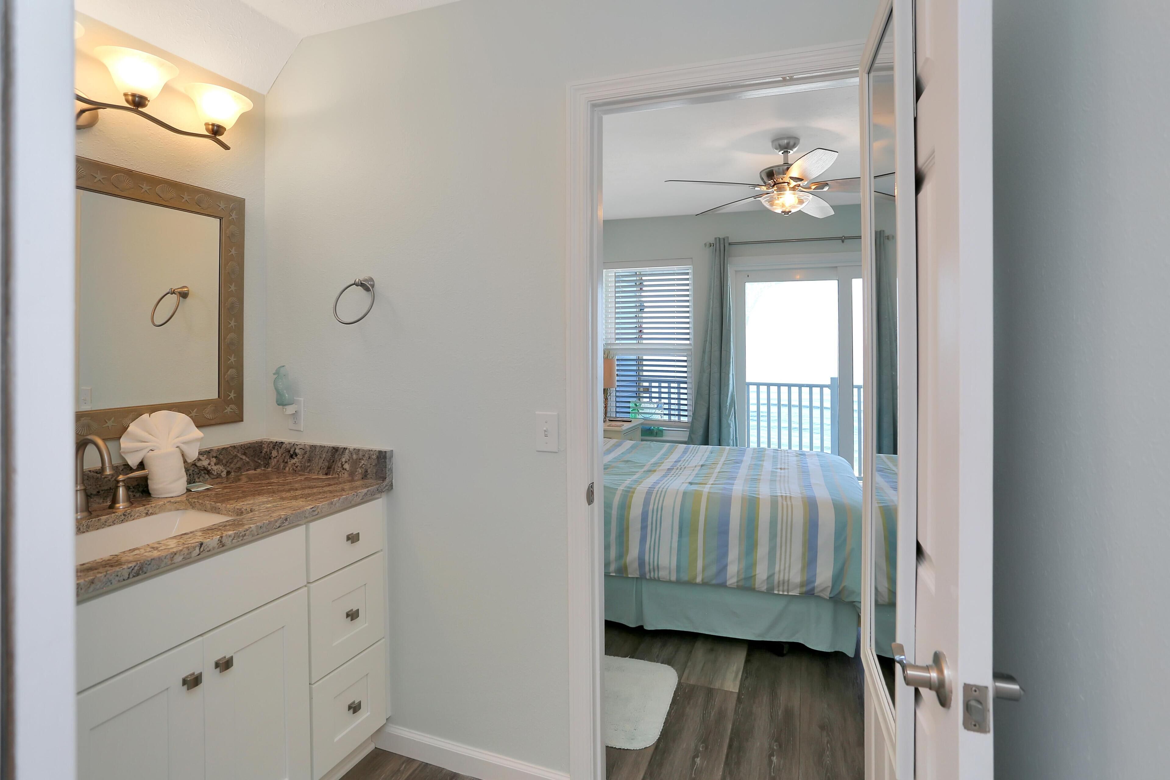A bathroom with a vanity, mirror, and a ceiling fan.