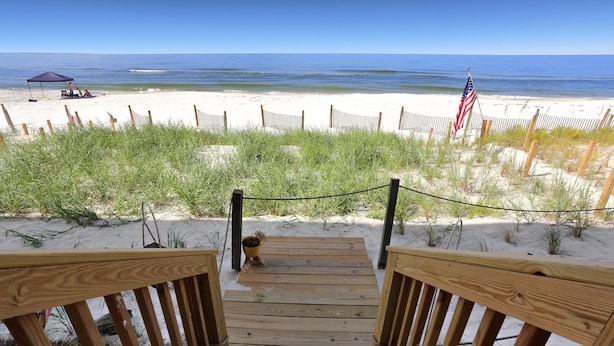 Un escalier en bois menant à une plage, avec une clôture et un drapeau américain.
