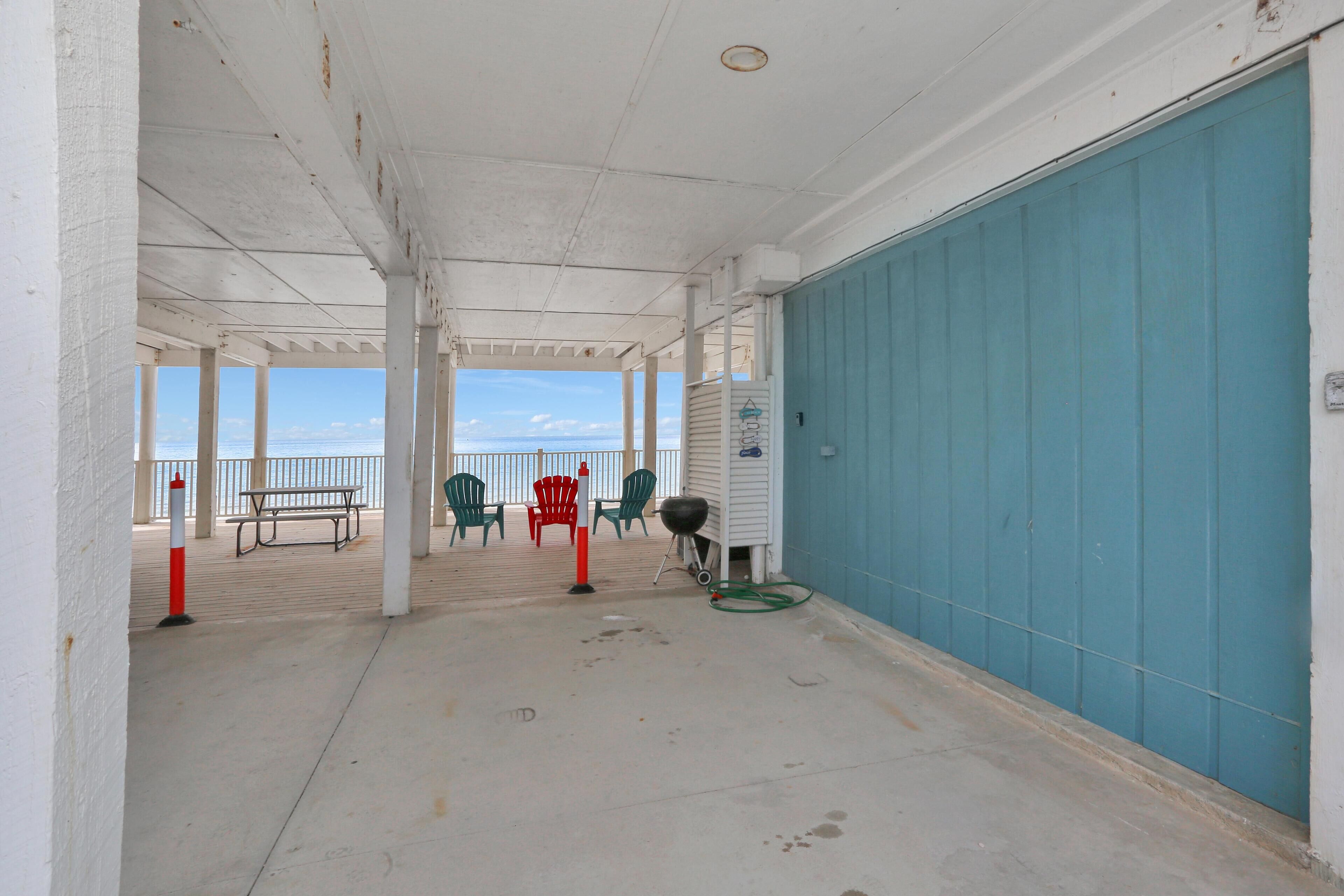Un espace extérieur abrité, avec vue sur la mer, comprenant une table de pique-nique, des chaises et un barbecue.