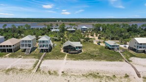 A coastal property with multiple beachfront houses, a sandy beach, and a view of the water and forest in the background. - WindScape (Port St. Joe)