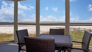 A covered outdoor seating area with wicker furniture and a view of the beach. - WindScape (Port St. Joe)