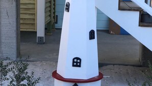 Une structure blanche, de style phare, avec une base rouge, une petite fenêtre et une porte.