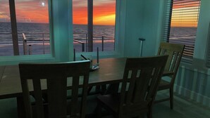 Un espace repas offrant une vue sur l’océan au coucher du soleil.