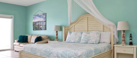 A bedroom with a bed, nightstands, a ceiling fan, a window, and a wall-mounted artwork.