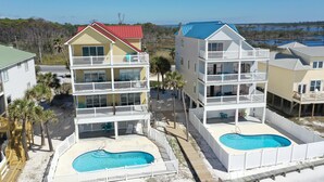 A beachfront hotel with multiple balconies, a swimming pool, and a view of the ocean.