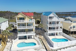Un hotel frente a la playa con varios balcones, piscina y vistas al océano.