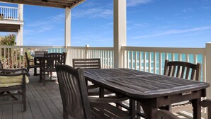 A covered outdoor seating area with wooden tables and chairs, overlooking a body of water.