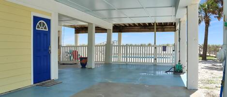 A covered outdoor area with a blue door, white fence, and a concrete floor.
