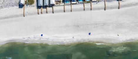 An aerial view of a beachside hotel with multiple buildings, a swimming pool, and a road parallel to the beach.