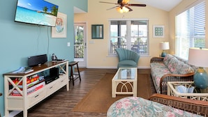 A living room with a television, a ceiling fan, a sofa, a chair, and a coffee table. - Sweet Destiny (Port St. Joe)