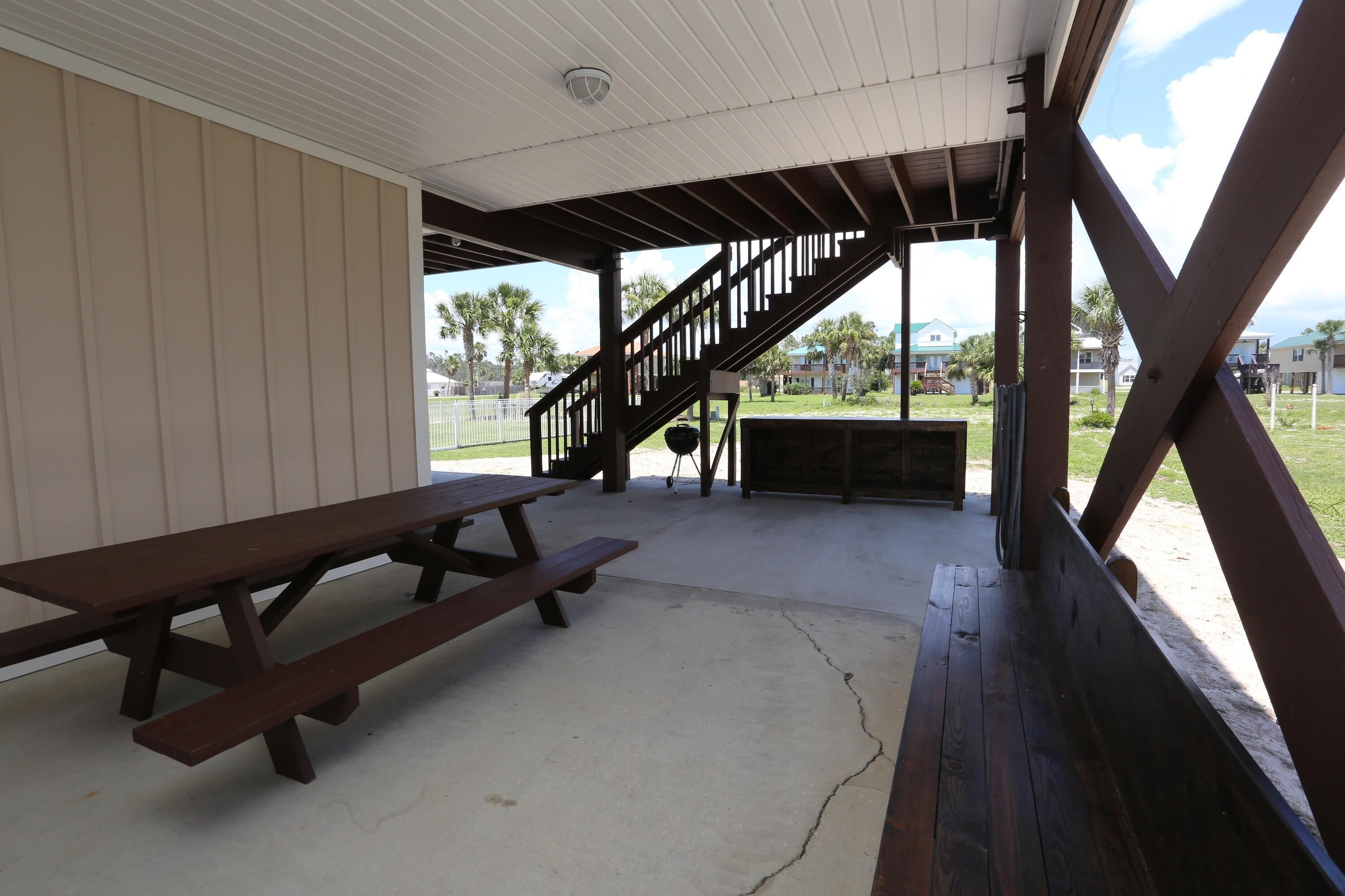 A covered picnic area with a wooden bench and a picnic table.