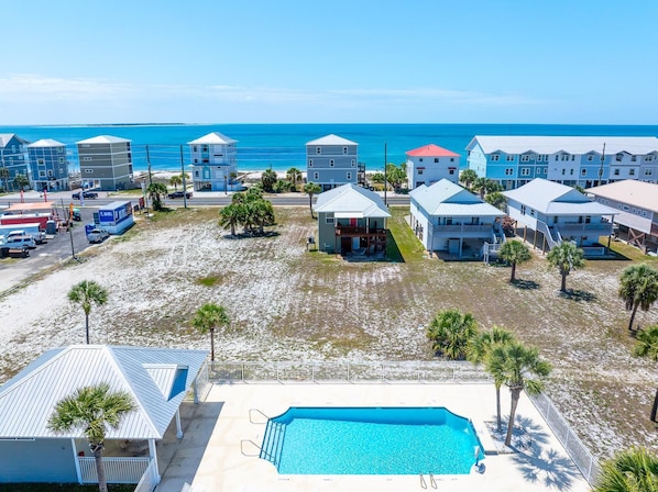 Ett hotell vid kusten med en swimmingpool, utsikt över stranden och flera byggnader.