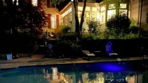 Nachtsicht auf ein Wohngebiet mit einem Schwimmbad, das umliegende Gebäude und Bäume reflektiert.