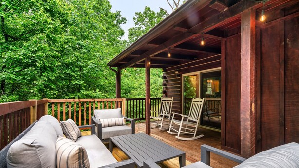 Eine Terrasse im Freien mit Holzmöbeln, darunter eine Sitzecke mit Sofa und Stühlen sowie ein Tisch.