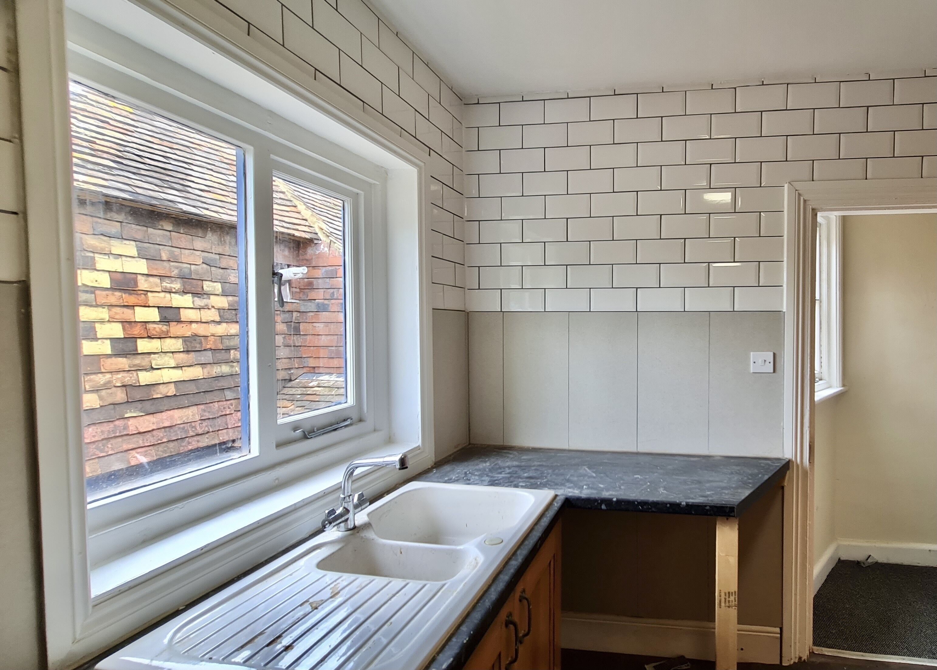 A kitchen with two sinks, a window, and a brick wall visible through the window.