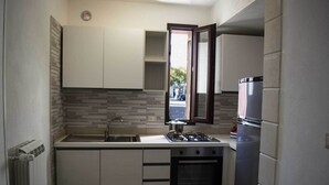 A compact kitchen with a gas stove, oven, and a refrigerator. - Casa Vacanze Mediterranea (Gagliano del Capo)
