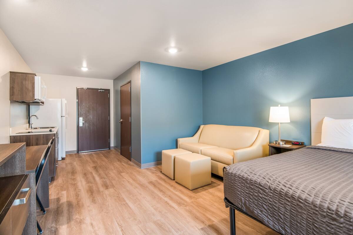 Une chambre d’hôtel avec un lit, un canapé, un bureau et une porte.