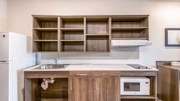 A kitchen with wooden cabinets, a white countertop, a sink, a microwave, and a refrigerator.