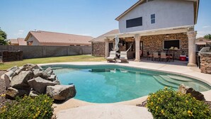 Ein Wohnhaus mit Swimmingpool, Steinterrasse und Sitzbereich im Freien.