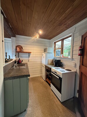 A compact kitchen with a wooden ceiling, a window, and a sink.