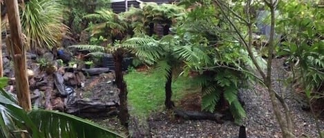 A garden with a small waterfall, rocks, and various plants.