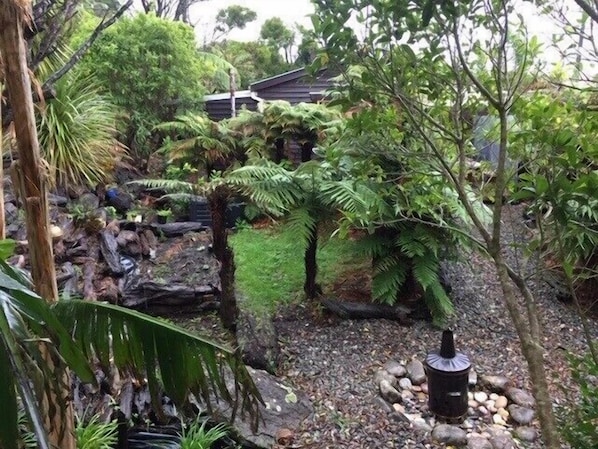 A garden with a small waterfall, rocks, and various plants. - Granity's Cosy Cottage (Granity)