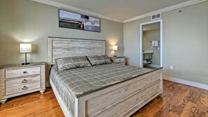Un dormitorio con una cama grande, dos mesitas de noche, un tocador, un espejo y un cuadro en la pared.