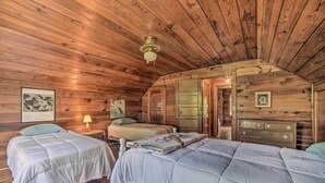 A cabin with two beds, wooden walls, a ceiling fan, and a framed picture on the wall. - Rustic Dover Retreat w/ Porch - Walk to Boat Ramp! (Dover)