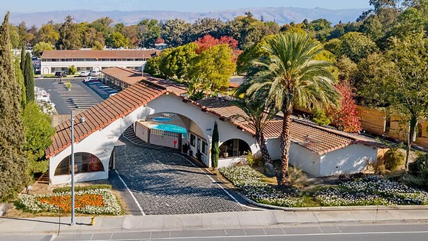 A hotel with a courtyard, palm trees, and a parking lot. - Super 8 by Wyndham San Jose Airport (San Jose)
