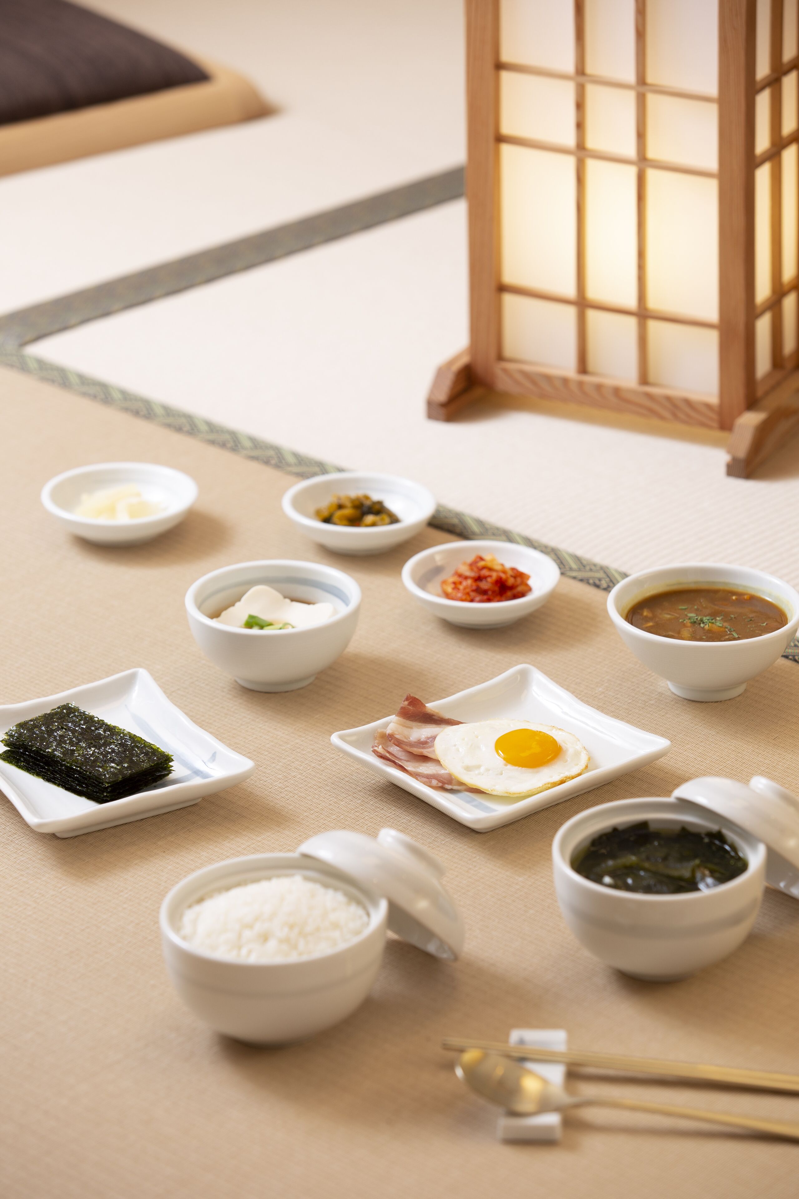 Un allestiment de menjar tradicional japonès amb diversos plats, com ara arròs, algues i sopa, disposats sobre un matalàss tatami.