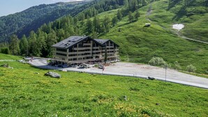 A multi-story building with balconies, surrounded by lush green hills and a clear sky. - Cosy apartment for 4 people with WIFI, TV and balcony (Basse-nendaz)