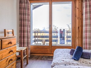 Ein Schlafzimmer mit einem hölzernen Schminktisch, einem Bett mit floralem Bettbezug und einer großen Schiebetür zu einer Außenterrasse.
