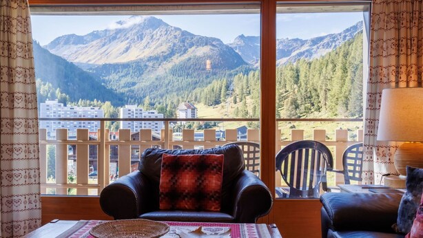 A balcony with a leather sofa and a table, overlooking a mountainous landscape with buildings in the background. - Nice apartment for 8 guests with WIFI, TV and terrace (Basse-nendaz)