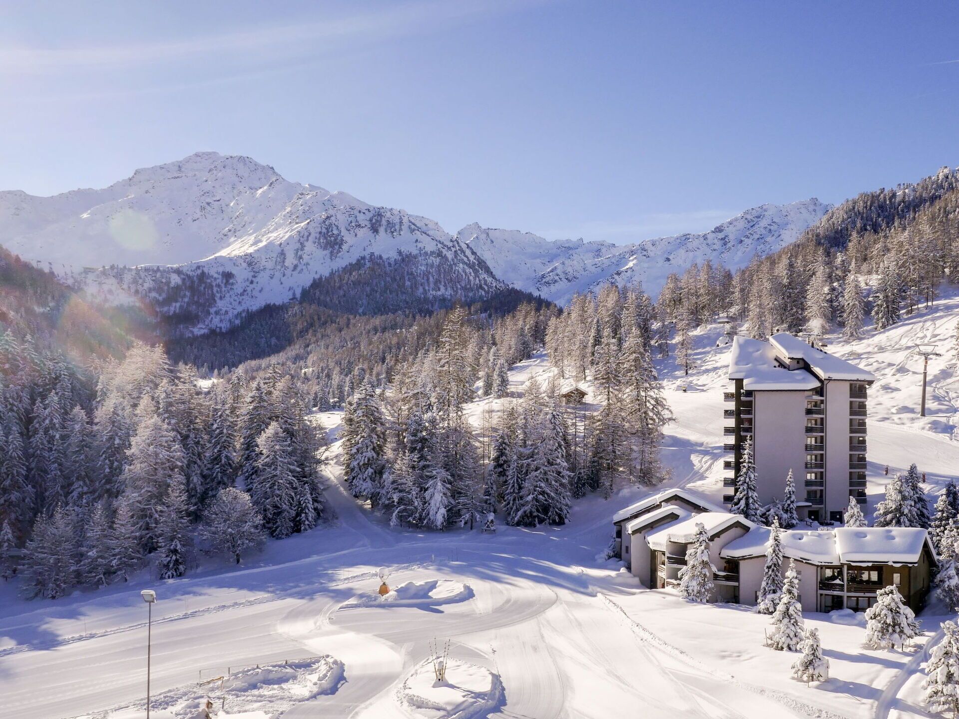 A snow-covered mountain resort with a ski slope, a lodge, and a view of the surrounding mountains.