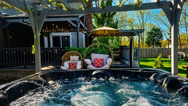 Ein Whirlpool mit zwei Stühlen, einer Pergola und einer Holzterrasse.