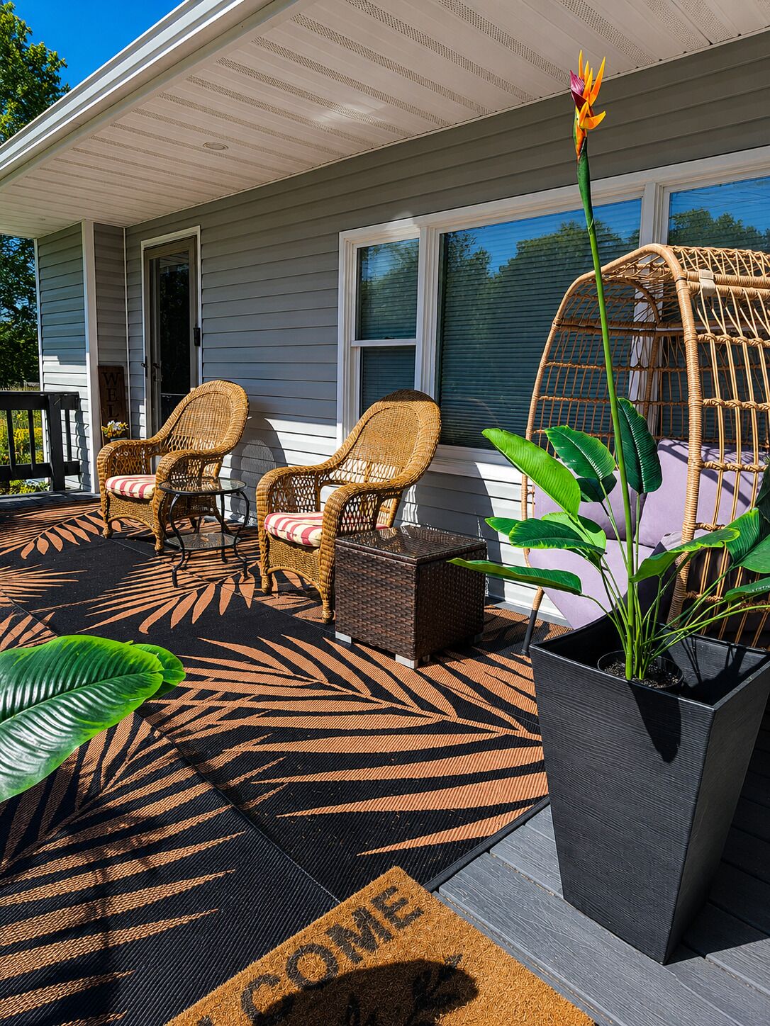 Eine Veranda mit Korbmöbeln, einer Fußmatte und einem Blumentopf.