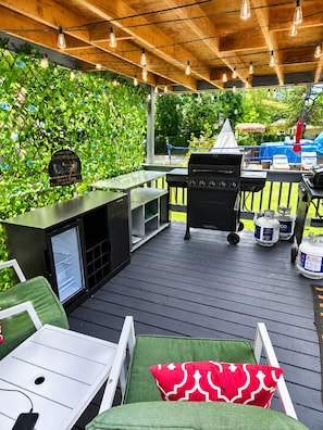 Eine überdachte Terrasse im Freien mit Grill, Sitzgelegenheit und einer begrünten Wand.