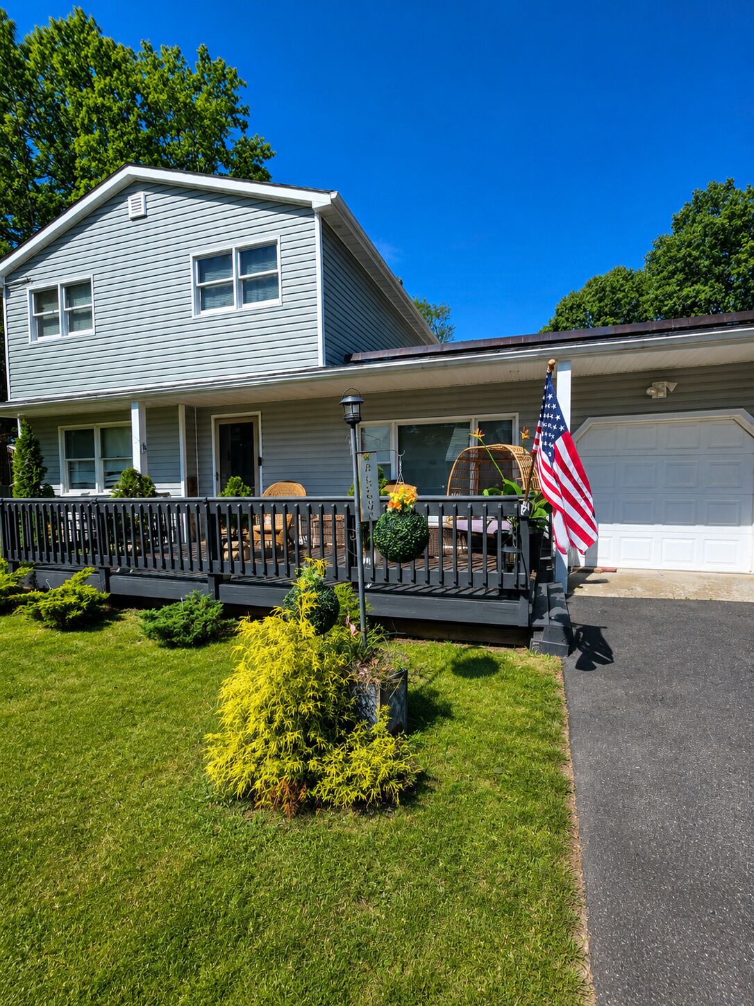 A two-story house with a front porch, a flag, and a garage.
