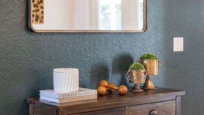 A wooden dresser with a mirror above it, a small plant, and a book titled "Curate." - 2 Acre FL Oasis with Game Room; Cozy+Quiet - Equestrian and Nature enthusiasts. (Ocala)
