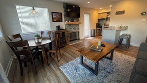 A modern living room with a wooden dining table, chairs, a coffee table, and a fireplace. - Mountain Top Adventure Condo (Gatlinburg)