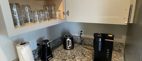 Une cuisine dotée de plans de travail en granit, d’une machine à café, d’un grille-pain et d’un porte-rouleau d’essuie-tout.