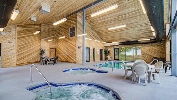 A spa area with hot tubs, wooden walls, and a seating area with tables and chairs. - Mountain Top Adventure Condo (Gatlinburg)