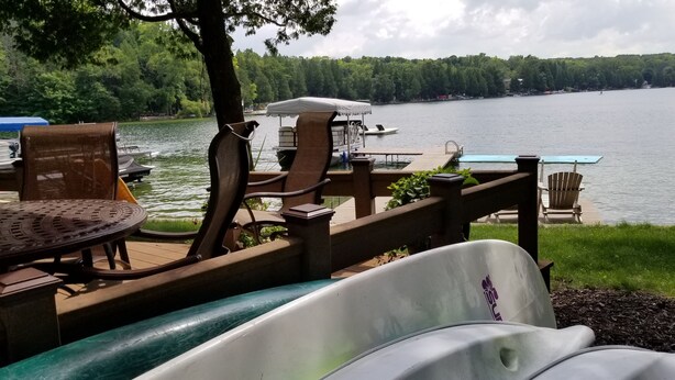 Terraza junto al lago con sillas, una mesa y una piscina pequeña.