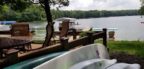 Terraza junto al lago con sillas, una mesa y una piscina pequeña.