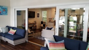 Una sala de estar moderna con un sofá, una silla roja y un comedor con mesa y sillas.