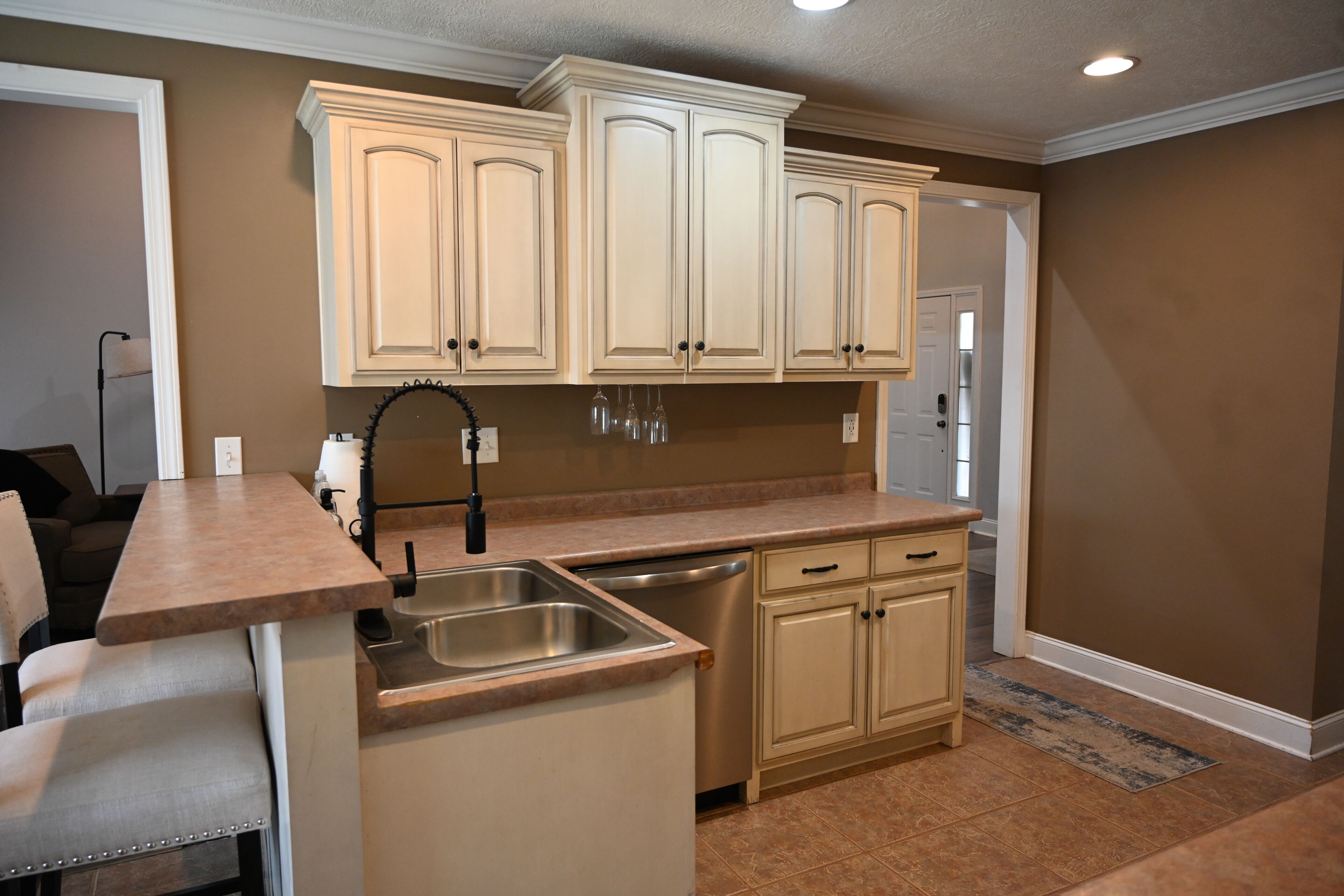 A compact kitchen with beige cabinets, a stainless steel sink, and a dishwasher.