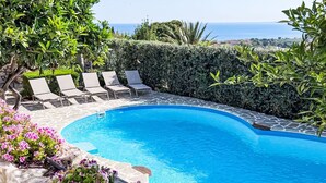 A swimming pool with clear blue water, surrounded by stone tiles and a hedge. - Lovely apartment for 2 guests with pool, WIFI, A/C and TV (Castellammare Del Golfo)