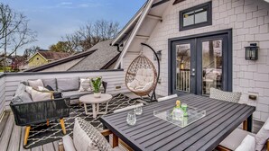A rooftop patio with a dining table, chairs, and a hanging chair. - Salt In The City a Downtown Retreat-Hidden rooftop with Downtown Skyline Views. (Nashville)