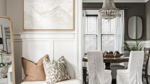 A modern living room with a white sofa set, a dining area with white chairs, a chandelier, and a large abstract painting. - Salt In The City a Downtown Retreat-Hidden rooftop with Downtown Skyline Views. (Nashville)